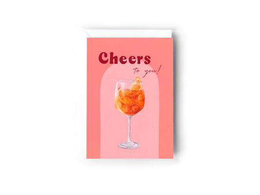 Cheers To You greeting card with an aperol spritz illustration on a salmon coloured background.